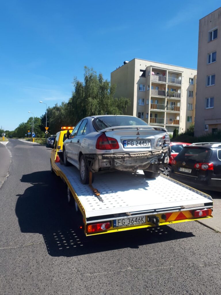 Holowanie Piła - samochód holowany przez specjalistyczną firmę holowniczą na autostradzie podczas zachodu słońca